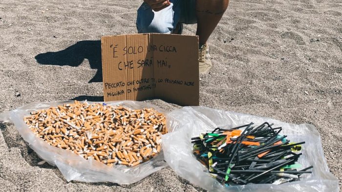 volontari ripuliscono la spiaggia della baia sabbia coperta da sigarette